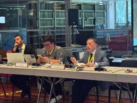 Tres hombres participan en una reunión en un ambiente moderno y organizado.