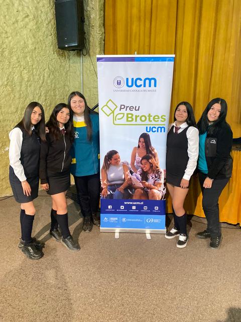 Grupo de seis jóvenes posando frente a un banner del programa Preu eBrotas de la UCM.