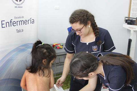 Dos estudiantes de enfermería están atendiendo a una niña en un ambiente clínico.