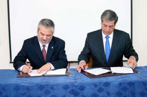 Dos hombres firmando un acuerdo en una mesa.
