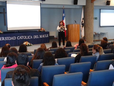 Una mujer está dando una charla en un auditorio lleno de gente en la Universidad Católica del Maule.