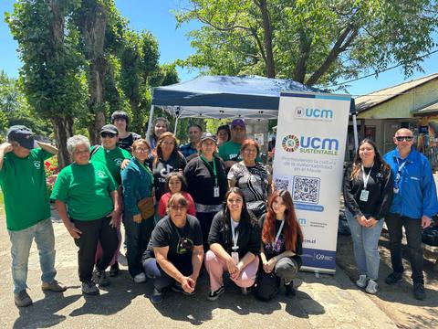 Un grupo de personas posando frente a una carpa de la organización UCM Sustentable en un día soleado.