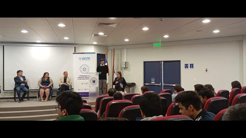 Una conferencia en un auditorio con varios ponentes y un público atento.