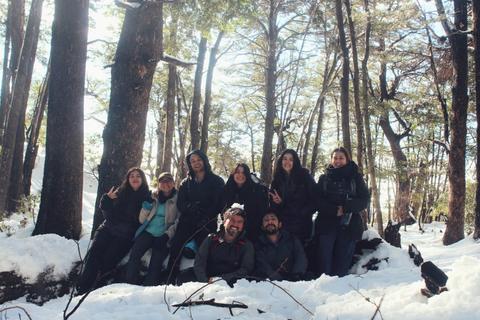 Un grupo de personas sonrientes posando en un paisaje nevado rodeado de árboles.