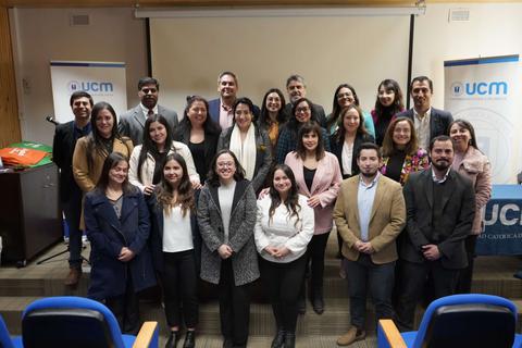 Un grupo de profesionales posan juntos en un evento, con un fondo que incluye el logo de UCM.