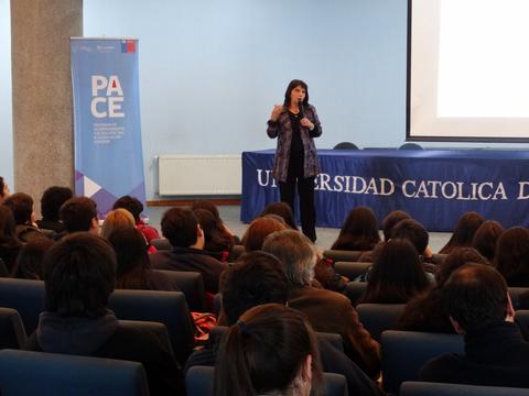 Una oradora presenta en una conferencia ante una audiencia en la Universidad Católica.