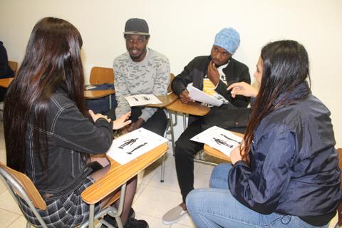 Un grupo de cuatro estudiantes discutiendo en un aula.