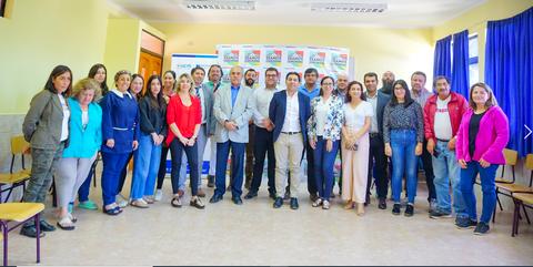 Un grupo de personas posando en una sala, algunas de ellas vestidas de manera formal y otras más casual.