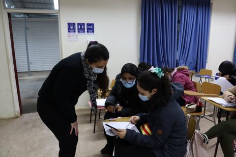 Un grupo de estudiantes discute sobre un trabajo en un aula mientras usan mascarillas.
