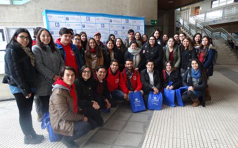 Un grupo de estudiantes posando juntos en un lugar interior, con bolsas azules y sonrisas.