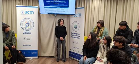 Un grupo de estudiantes escucha a una docente en una charla sobre educación matemática.
