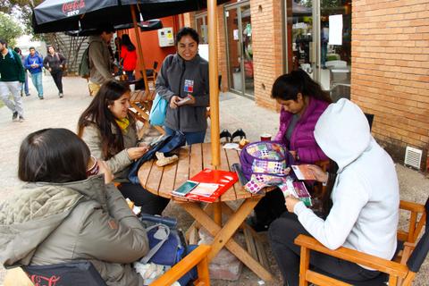 Un grupo de cinco personas sentadas en una mesa al aire libre, revisando documentos y conversando entre ellas.
