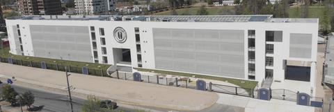 Edificio moderno de color blanco con diseño contemporáneo y áreas verdes en su entorno.