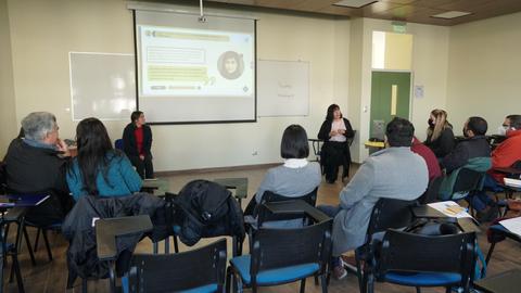 Un grupo de personas asiste a una presentación en un aula con una proyección en la pared.
