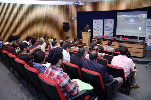 Una sala de conferencias con un orador frente a una audiencia atenta.