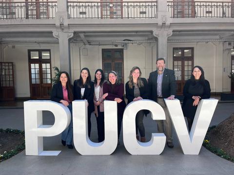 Un grupo de personas posando frente a letras gigantes que representan la PUCV.