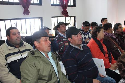 Un grupo de personas sentadas en un salón, escuchando atentamente.