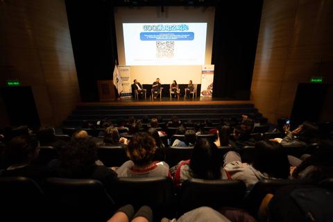 Una audiencia observa un panel de discusión en un auditorio.