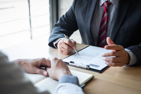 Dos personas en una reunión discutiendo un documento sobre una mesa.