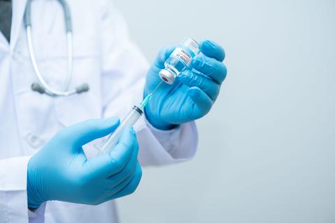 Un profesional de la salud sostiene una jeringa y un vial de medicamento.