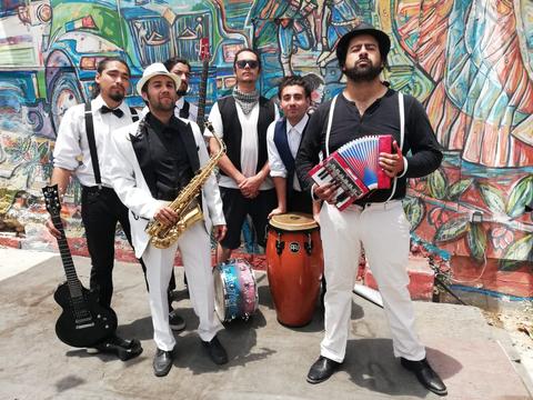 Un grupo de músicos posando juntos frente a un mural colorido.
