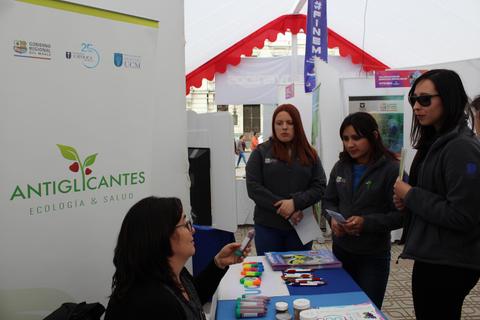 Un grupo de mujeres conversando en un stand sobre ecología y salud en un evento al aire libre.