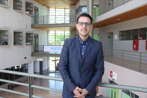 Un hombre vestido de traje se encuentra en un espacio interior moderno con grandes ventanales.