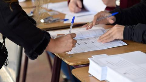 Personas completando formularios en un banco de mesas.