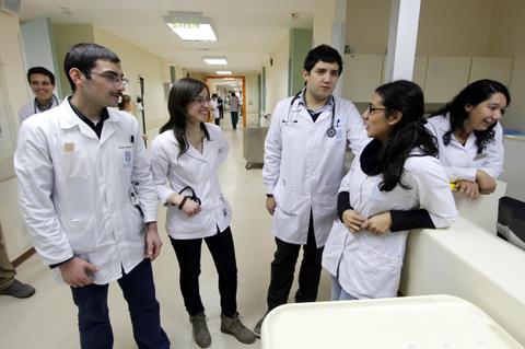 Un grupo de estudiantes de medicina conversando en un pasillo de hospital.