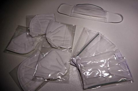 La imagen muestra varias mascarillas blancas empaquetadas y una mascarilla suelta en la parte superior.