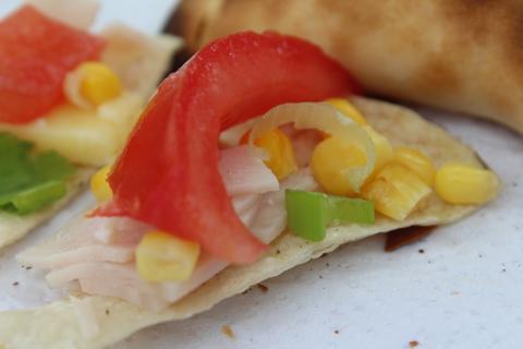 Una tortilla con ingredientes frescos como pimiento, tomate, maíz y pollo.