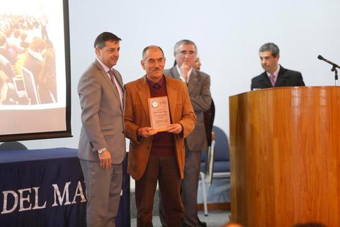 Un hombre recibe un reconocimiento en un evento formal.