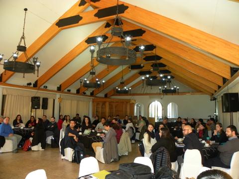 Una sala amplia con muchas personas sentadas en mesas, durante un evento o reunión.