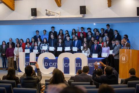 Ceremonia de entrega de diplomas en la Universidad Católica del Maule con un grupo de graduados y sus familias.