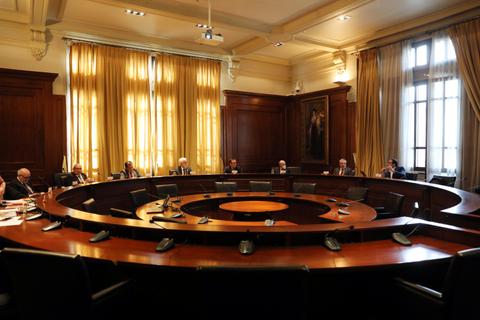 Una sala de reuniones con una mesa circular y varias personas sentadas alrededor.