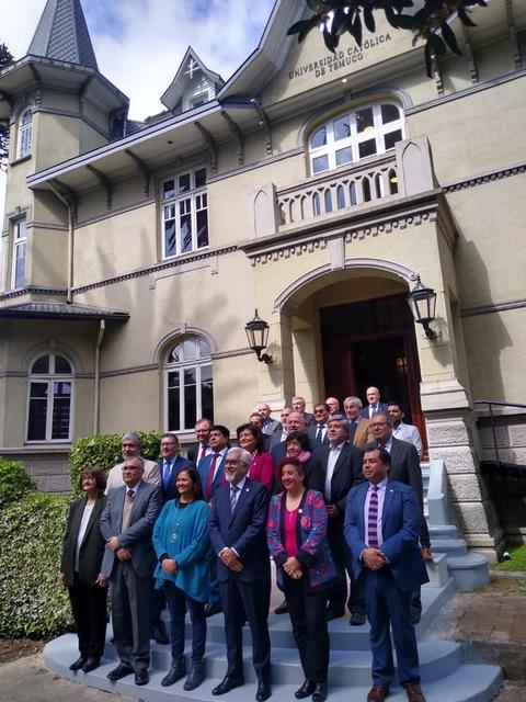 Un grupo de personas posando frente a un edificio de la Universidad Católica de Valparaíso.