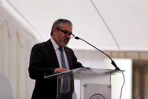 Un hombre con gafas está hablando en un podio durante un evento formal.