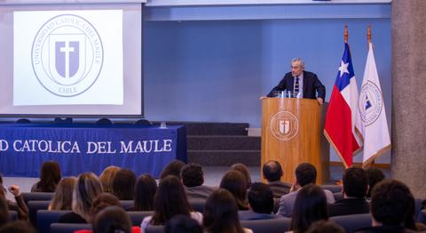 Un orador presenta en un auditorio lleno de asistentes en la Universidad Católica del Maule en Chile.