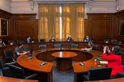 Una sala de reuniones con varias personas sentadas alrededor de una mesa circular.