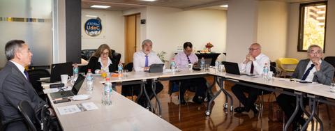 Una reunión de trabajo con varias personas sentadas alrededor de una mesa.