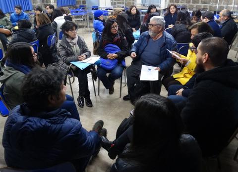 Un grupo de personas sentadas en círculo, participando en una conversación en un ambiente comunitario.