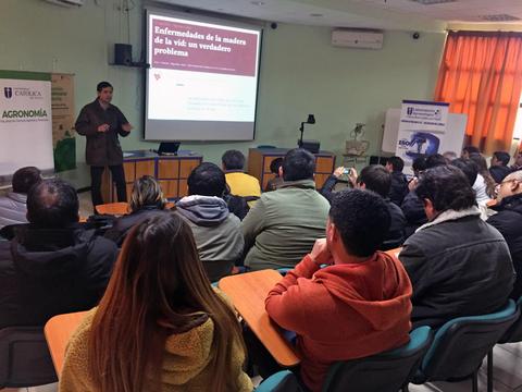 Una conferencia sobre enfermedades de la madre de la vid con un ponente frente a un grupo de asistentes.