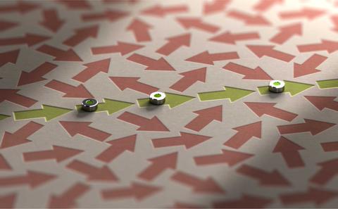 La imagen muestra una serie de flechas de color rojo y verde dispuestas sobre una superficie, donde hay tres objetos metálicos alineados en el centro.