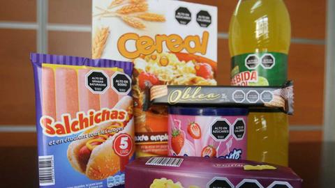 La imagen muestra una variedad de productos alimenticios, incluyendo cereales, salchichas, obleas y una bebida.