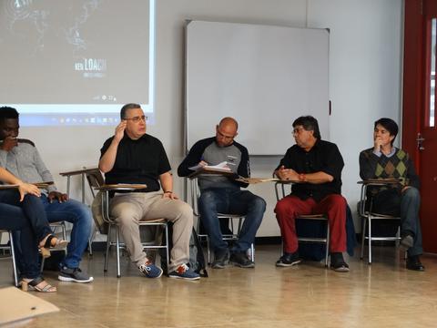 Un grupo de personas sentadas en una sala discutiendo en un ambiente de trabajo colaborativo.