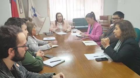 Una reunión de grupo en una sala con varios participantes discutiendo alrededor de una mesa.