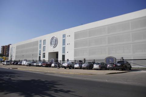 Edificio grande y moderno con varios vehículos estacionados frente a él.