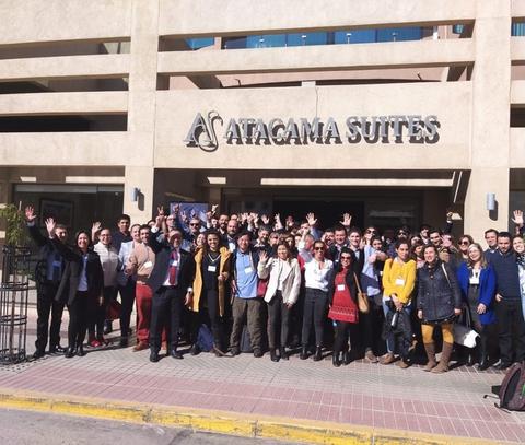Un grupo numeroso de personas se reúne frente a un edificio que lleva el nombre 'Atacama Suites'.