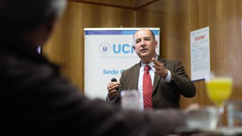 Un hombre está dando una charla en un evento académico.