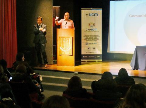 Un orador se presenta en un escenario durante un evento, mientras un intérprete de lengua de señas lo acompaña.